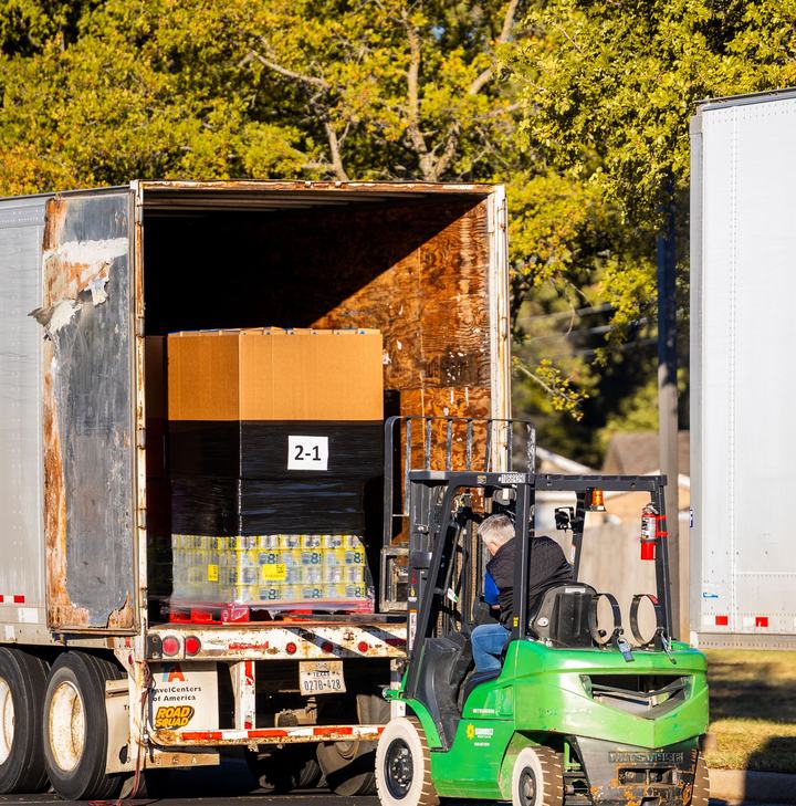 Forklift loading pallets into a dry van trailer at a shipping dock