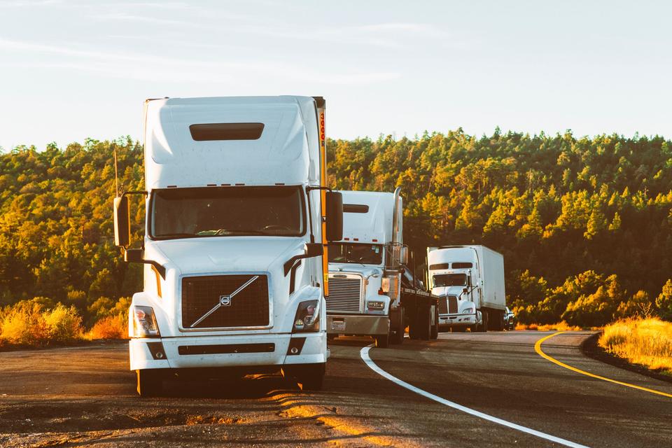 White semi trucks with dry van and flatbed trailers on a US highway at golden hour